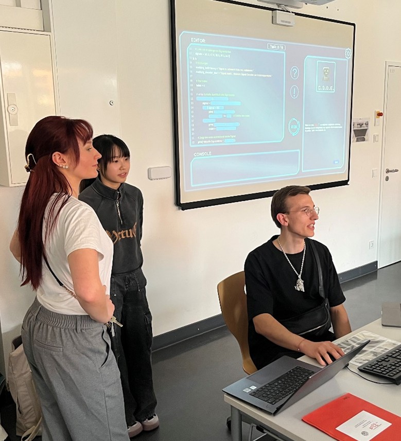Zu sehen sind zwei Informatikstudentinnen und ein Informatikstudent der TU München.