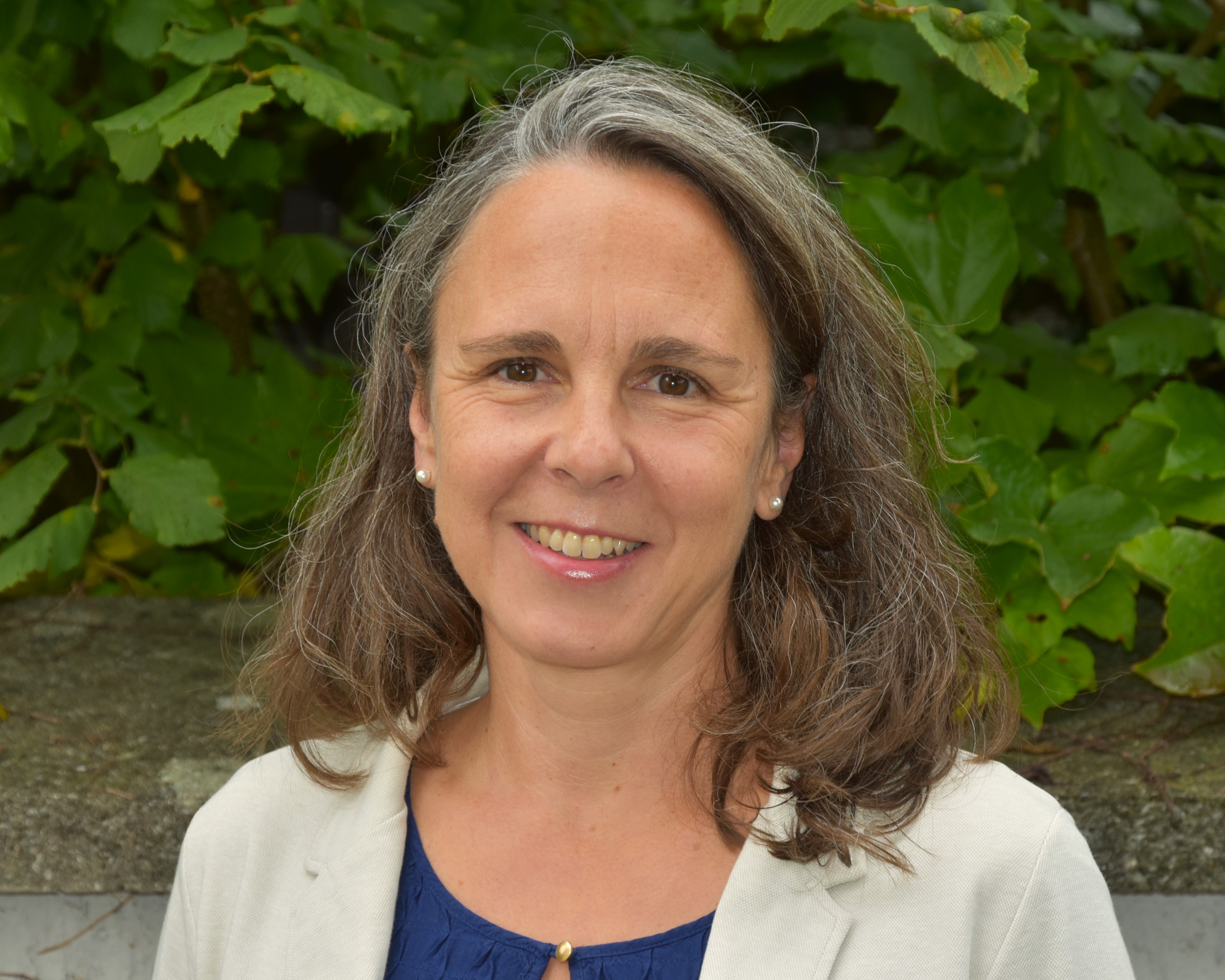 Porträt eines Mitglieds der Erweiterten Schulleitung, aufgenommen vor einem blauen Hintergrund.