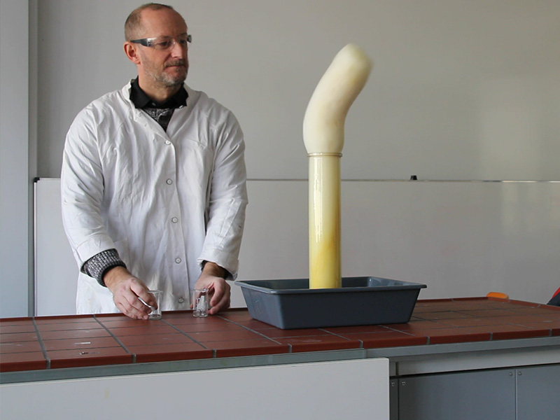 Ein Chemielehrer stellt "Elefantenzahnpasta" her. Sichbar ist eine (Redox-)Reaktion, bei der eine größere Menge an Schaum entsteht.