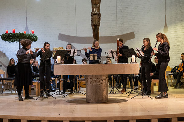 Schülerinnen und Schüler musizieren auf ihren Holzblasinstrumenten in einem Kirchenraum.