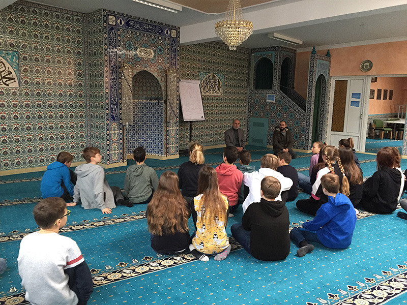 Kinder sitzen in einer Moschee.