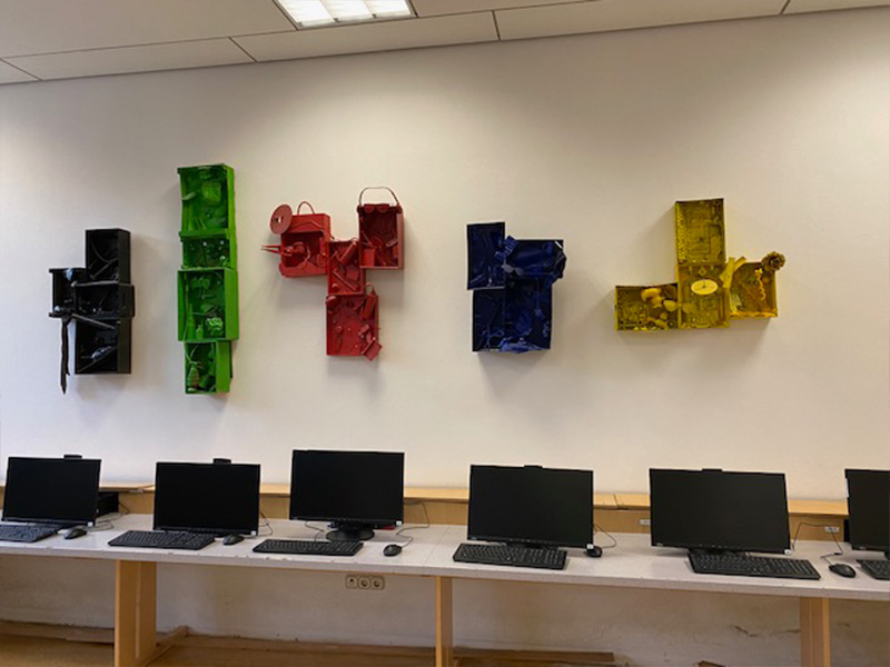 Sechs Computer im Computerraum des Gymnasiums stehen für digitales Arbeiten bereit. Die Wandkunst in fünf verschiedenen Farben verleiht dem Raum eine inspirierende Gestaltung.
