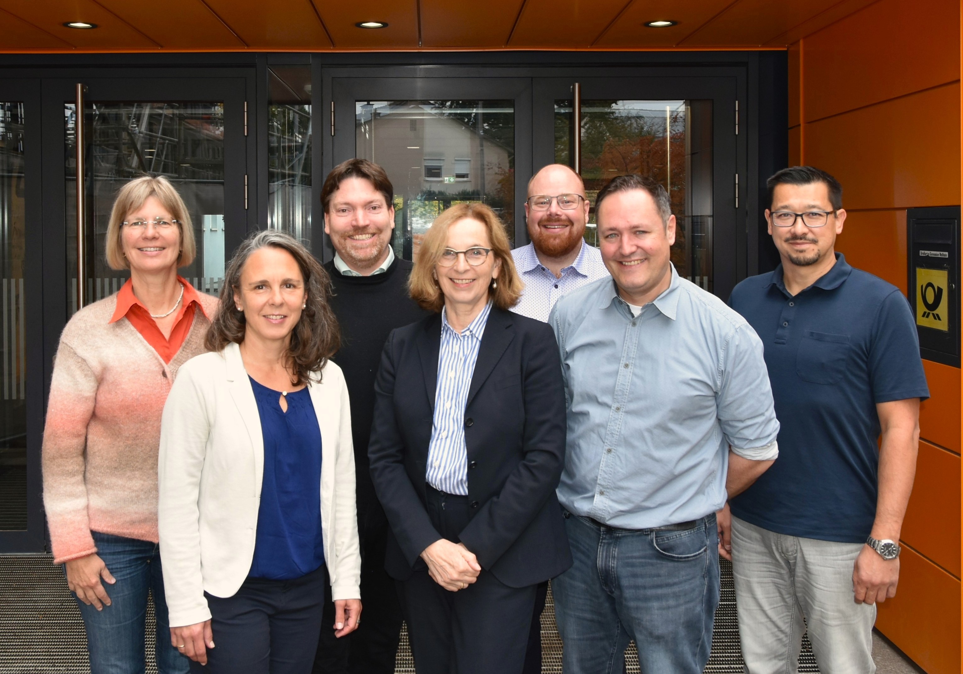 Bild aller Mitglieder der Schulleitung vor einer Schuleingangstür.