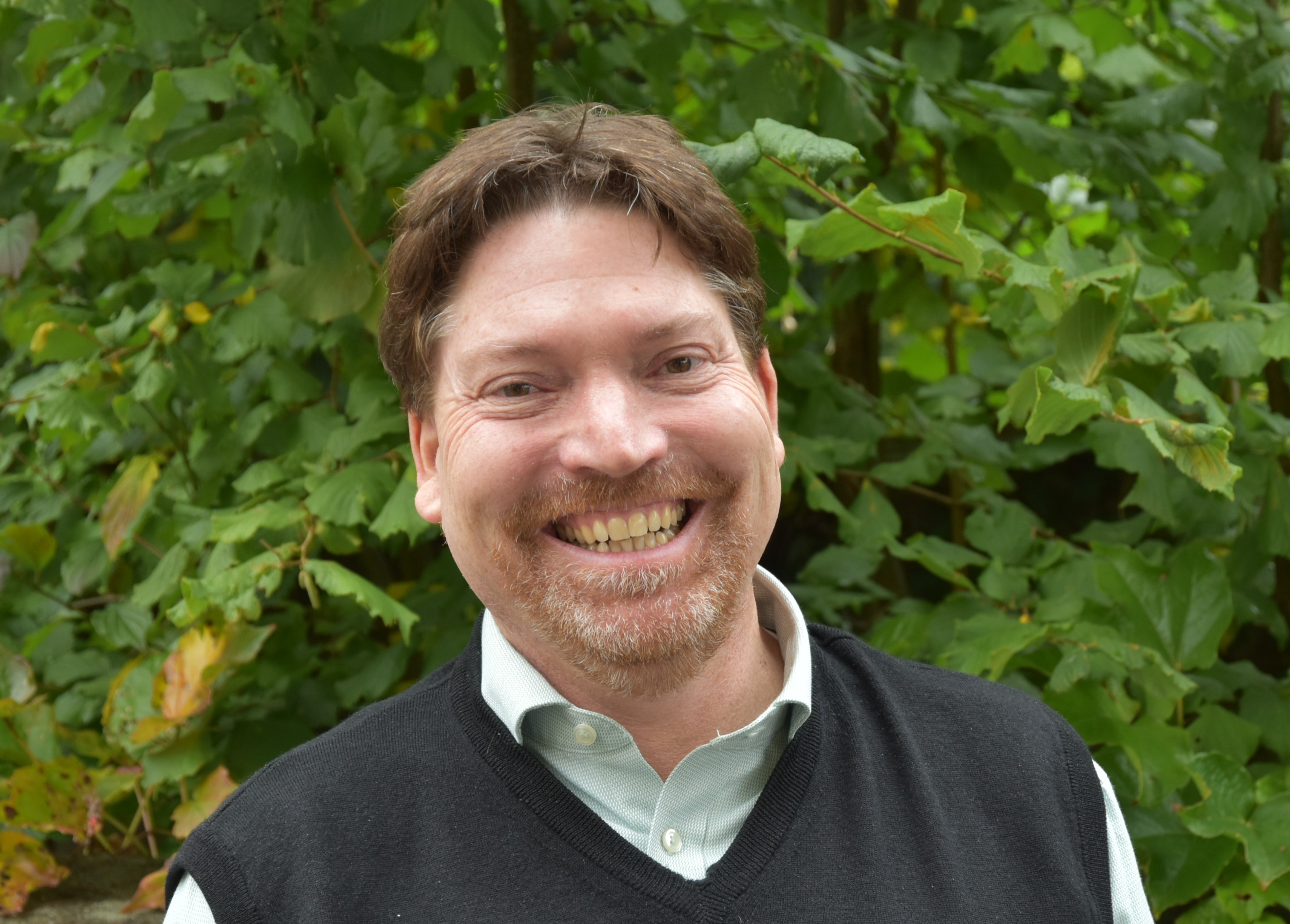 Porträt des Stellvertretenden Schulleiters, aufgenommen vor einem blauen Hintergrund.